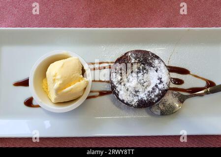 Schokoladen-Cupcake, Muffin, Kuchen mit Eis auf weißem Teller im Restaurant, Café. Kuchen zum Frühstück, Nachtisch Stockfoto