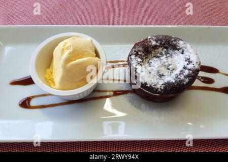 Schokoladen-Cupcake, Muffin, Kuchen mit Eis auf weißem Teller im Restaurant, Café. Kuchen zum Frühstück, Nachtisch Stockfoto