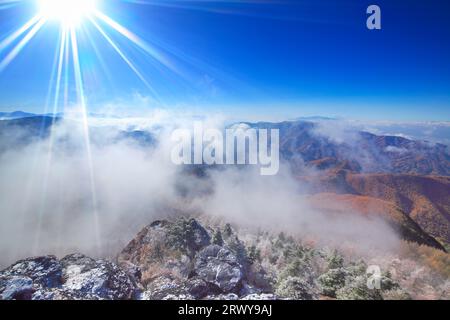 Morgensonne, aufgehende Wolken, Neuschnee auf dem felsigen Bergrücken von Oogahana, Mt. Fuji und andere Bergketten Stockfoto