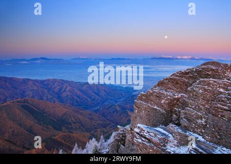 Der felsige Kamm von Oogahana mit frischem Schnee, der Mond am Morgen und ein weiter Blick auf die Hotaka-Bergkette und andere Gipfel Stockfoto