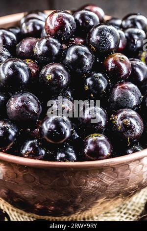 Jabuticaba. Brasilianische und südamerikanische tropische Früchte, in einem Kupfertopf auf einem rustikalen Tisch Stockfoto