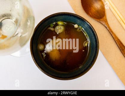 In einer tiefen dunklen Schüssel eine Portion Miso-Vermicelli-Suppe mit jungen Zwiebelgemüse. Stockfoto