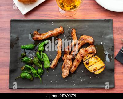 Frittierte iberische Träne, dünne Streifen Schweinefilet gegrillt mit grünem Pfeffer und Kartoffelscheibe Stockfoto