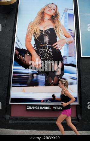 Eine junge Frau joggt an einem Poster der Schauspielerin Sydney Sweeney aus dem Musikvideo für den Song Angry der Rolling Stones vorbei, der auf The Whisky, L.A., CA veröffentlicht wurde. Stockfoto