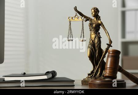 Figur der Lady Justice, Hammer und Notizbücher auf dem Tisch drinnen, Platz für Text. Symbol der gerechten Behandlung nach dem Gesetz Stockfoto