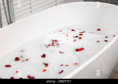 Badewanne mit Rosenblättern und Schaum im Badezimmer Stockfoto