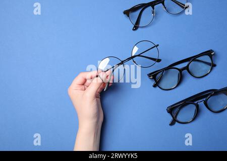 Frau mit verschiedenen stilvollen Brillen auf blauem Hintergrund, Draufsicht Stockfoto