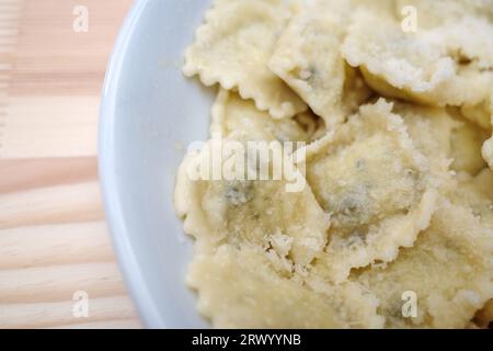 Oben und aus der Nähe Blick auf Ravioli mit Parmesankäse auf dem Holztisch. Stockfoto