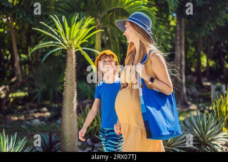 Werdende Mutter und ihr Sohn genießen einen gemütlichen Spaziergang im Park und genießen kostbare Momente inmitten der Schönheit der Natur Stockfoto