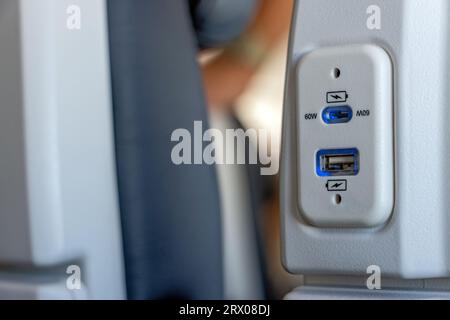 USB-Anschluss am Sitz des Flugzeugs zum Aufladen der elektronischen Geräte auf Reisen Stockfoto