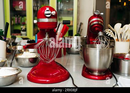 Roter Küchenmixer auf der Arbeitsfläche. Küchenutensilien und -Werkzeuge. Vorbereitung auf den kulinarischen Kurs. Stockfoto