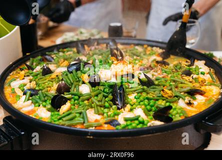 Kochen von Paella mit Meeresfrüchten und Gemüse in einem kulinarischen Meisterkurs. Große Paella-Pfanne zum Dampfgaren. Stockfoto