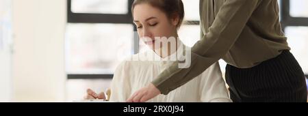 Frau, die auf Dokumente zeigt, während sie in der Nähe ihres jungen Managers steht. Stockfoto