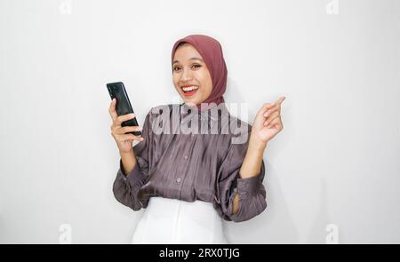 Porträt einer glücklichen jungen muslimischen Frau, die auf dem Handy vor weißem Hintergrund spricht Stockfoto