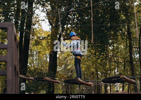 Teenager-Boyin Outdoor-Abenteuerpark, der Hindernisparcours passiert. Hochseilpark. Hochwertige Fotos Stockfoto