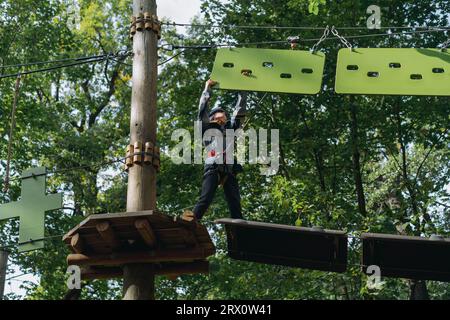 Teenager-Boyin Outdoor-Abenteuerpark, der Hindernisparcours passiert. Hochseilpark. Hochwertige Fotos Stockfoto