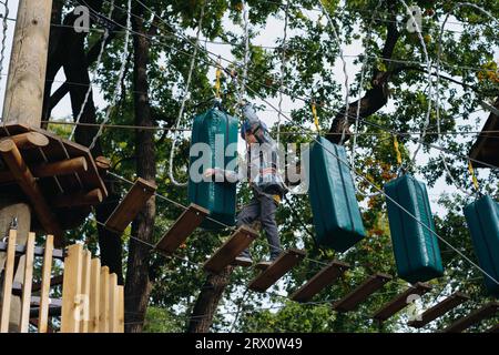 Teenager-Boyin Outdoor-Abenteuerpark, der Hindernisparcours passiert. Hochseilpark. Hochwertige Fotos Stockfoto