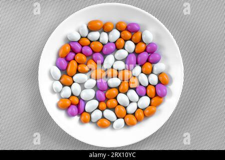 Glasierte Erdnüsse in verschiedenen Farben auf einem Teller. Bunte Erdnüsse. Nahaufnahme. Erdnüsse, Kerne, Haselnüsse, Nüsse, Cashew. Stockfoto