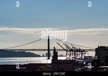 Ein Blick auf Lissabons 25 de Abril Brücke über den Fluss Tejo, mit dem riesigen Rua Augusta Arch (Arco do Triunfo) in der Mitte des Bildes Stockfoto