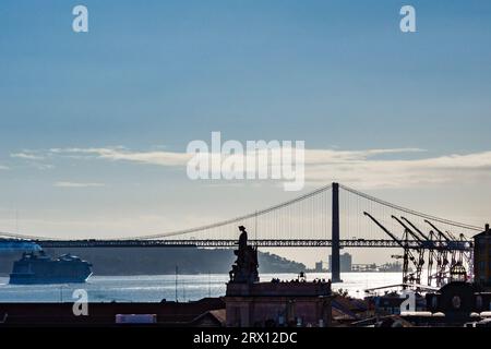 Ein Blick auf Lissabons 25 de Abril Brücke über den Fluss Tejo, mit dem riesigen Rua Augusta Arch (Arco do Triunfo) in der Mitte des Bildes Stockfoto