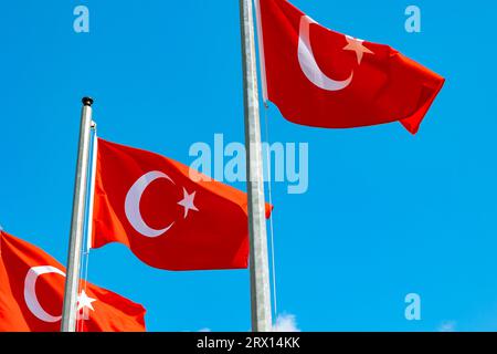 Drei türkische Flaggen winken auf dem Fahnenmast isoliert auf blauem Himmel Hintergrund. Hintergrundfoto der türkischen Nationalfeiertage. Stockfoto