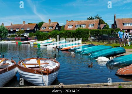 Die Meare im Thorpeness Suffolk zeigt farbenfrohe Ruderboote, Kanus, Schwäne und Enten Stockfoto