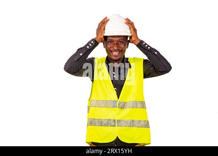 Hübscher junger Ingenieur, der einen weißen Schutzhelm trägt, während er lächelt. Stockfoto