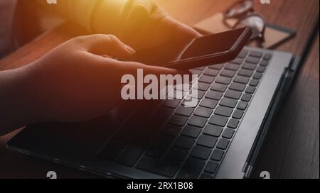 Geschäftsfrau, die am Schreibtisch mit Smartphone und Laptop arbeitet. Stockfoto