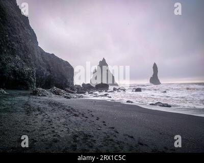 Schwarzer Sandstrand mit Felsformationen im Hintergrund Stockfoto