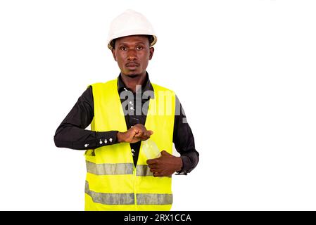 Junger Techniker mit grüner Weste und Schutzhelm, der die Mineralwasserflasche aus Kunststoff öffnet. Stockfoto