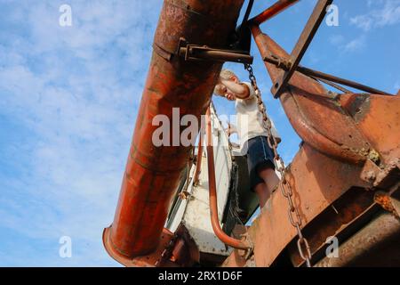 Ein kleiner Junge spielt auf einem alten Erntemaschine Stockfoto