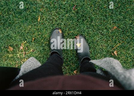 Regenstiefel bedeckt mit von oben gefallenen Blättern, Herbstmotiv Stockfoto