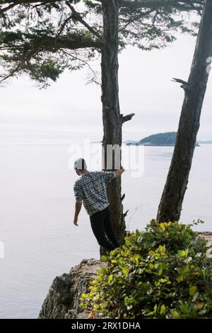 Mann in Beanie mit Blick auf das Meer von den Klippen Stockfoto