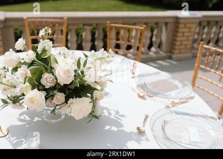 Weiße Rosen zieren den Tisch bei elegantem Hochzeitsempfang. Stockfoto