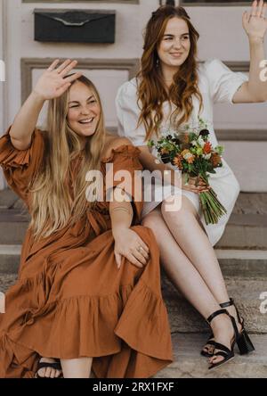 Zwei Schwestern winken den vorbeiziehenden Menschen zu Stockfoto