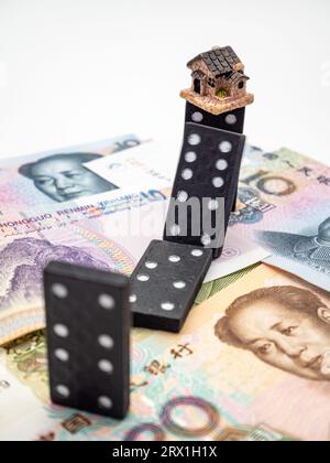 domino-Effekt und Haus auf chinesischer Yuan-Währung Hintergrund Konzeptfoto Stockfoto