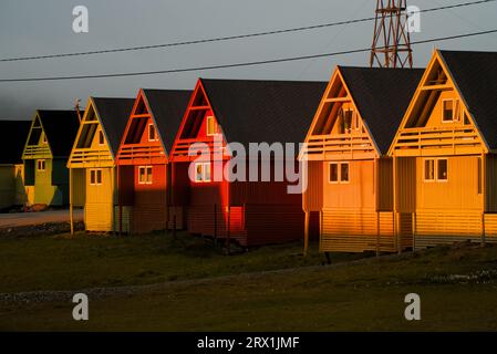 Eine Reihe farbenfroher skandinavischer Häuser während des ersten Sonnenuntergangs der Saison in Longyearbyen, Svalbard, Norwegen Stockfoto