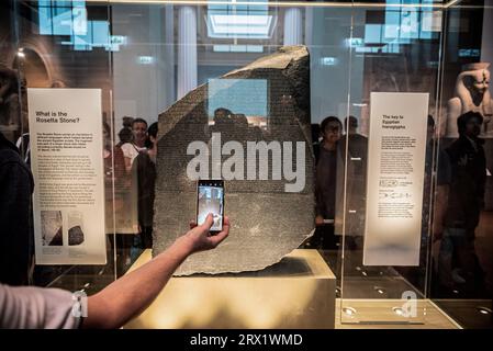 London, Großbritannien. August 2023. Ein Tourist macht ein Foto des Rosetta-Steins, der im British Museum in London ausgestellt ist. Die altägyptische Stele ist der Schlüssel zur Entzifferung der Hieroglyphenschrift. (Foto: John Wreford/SOPA Images/SIPA USA) Credit: SIPA USA/Alamy Live News Stockfoto