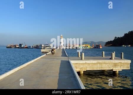 Betonpier mit Leuchtturm und Booten am anderen Ende in Bang Bao Bay, Ko Chang Insel, Thailand Stockfoto