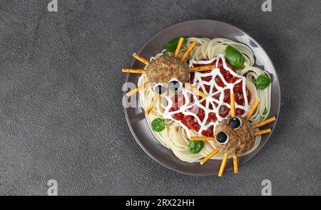 Schnitzel sehen aus wie Spinnen mit Oliven und Strohhalmen, serviert mit Spaghetti-Pasta und Tomatensauce. Halloween-Frühstücksidee, Blick von oben Stockfoto