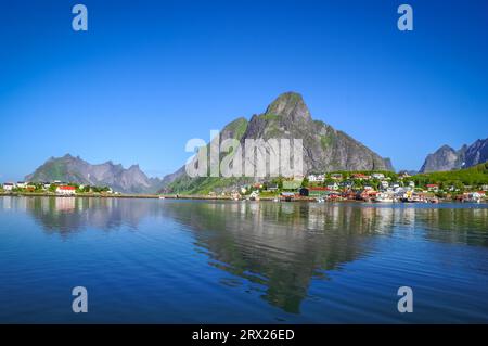 Foto von Wasser und Küste mit Häusern umgeben von hohen Bergen in der Nähe von Vindstad in Norwegen Stockfoto