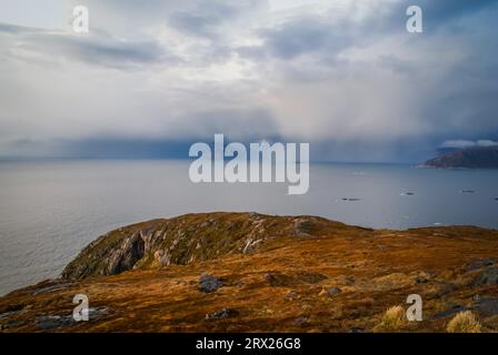 Foto von Klippen und Meer in der Entfernung bedeckt mit Nebel in Sommaroy, Norwegen Stockfoto
