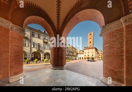 Alba, Langhe, Piemont, Italien - 20. August 2023: Piazza Risorgimento, historisches Stadtzentrum mit mittelalterlichem Turm, von den Arkaden der Kathedrale aus gesehen Stockfoto