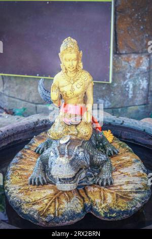 Alte goldene Statue Göttin Dharani Mata auf Krokodil im thai-Tempel. Antike Goldskulptur der Mutter Erde auf Alligator in Schrein in Phuket, Thailand Stockfoto
