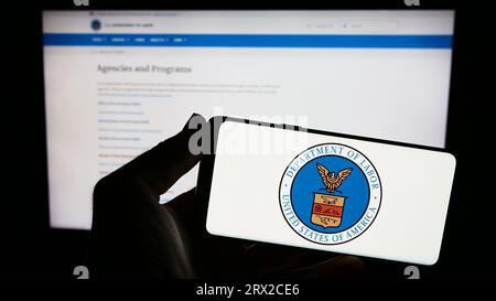 Person, die ein Smartphone mit dem Siegel des United States Department of Labor (US DOL) auf dem Bildschirm vor der Website hält. Konzentrieren Sie sich auf das Display des Telefons. Stockfoto