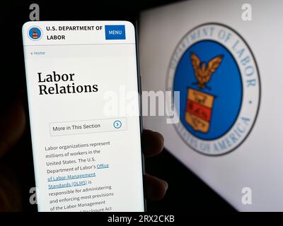 Person, die ein Smartphone mit einer Webseite des United States Department of Labor (US DOL) auf dem Bildschirm mit Siegel hält. Konzentrieren Sie sich auf die Mitte der Telefonanzeige. Stockfoto