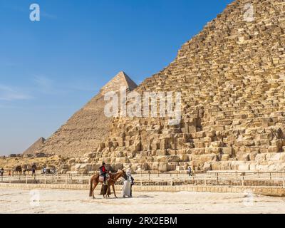 Touristen auf einem Kamelritt vor der Großen Pyramide von Gizeh, dem ältesten der sieben Weltwunder, Gizeh, in der Nähe von Kairo, Ägypten Stockfoto