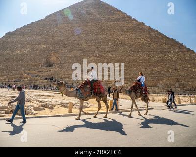 Tourist auf einem Kamelritt vor der Großen Pyramide von Gizeh, dem ältesten der sieben Weltwunder, in der Nähe von Kairo, Ägypten Stockfoto