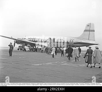 Fluggäste in den 1950er Jahren Ein viermotoriges Passagierflugzeug des Typs SE-BDM Douglas DC-6-477B Cloudmaster der skandinavischen Fluggesellschaft SAS steht an einem schwedischen Flughafen an, und die Fluggäste haben begonnen, die Treppe hinaufzusteigen und an Bord des Flugzeugs zu gehen. Das Wetter ist ein wenig grau und langweilig und man kann spekulieren, dass die Schweden, die mit Charterreisen nach Südeuropa begonnen haben, möglicherweise auf dem Weg dorthin sind, wo es sonnig und warm ist und so das trübe Wetter vermeiden. Schweden 1952. Kristoffersson ref BG60-4 Stockfoto