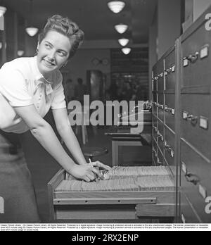 Frau im Büro in den 1940er Jahren Frau Karin Halvarsson in einer weißen Bluse und einem Rock bei der Arbeit im Amt für staatliche Interessen. Sie steht in einem Aktenschrank, wo sie Dokumente in einer erweiterten Aktenschublade durchblättert. Schweden 1942. Kristoffersson ref B88-4 Stockfoto